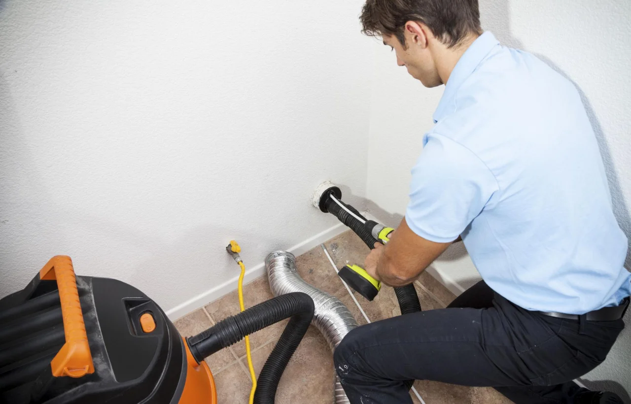 Technician cleaning dryer vent duct with vacuum equipment to remove lint buildup